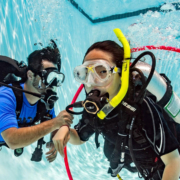 kids of 8 years old learning to scuba dive in the safe environemnt of a swimming pool with a professional diving instructor