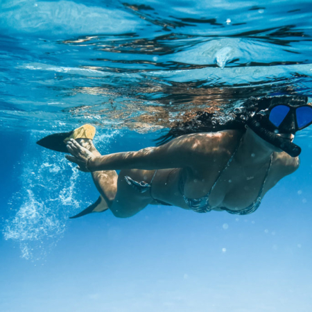 woman wearing mask and snorkel is swimming on the sea surface.