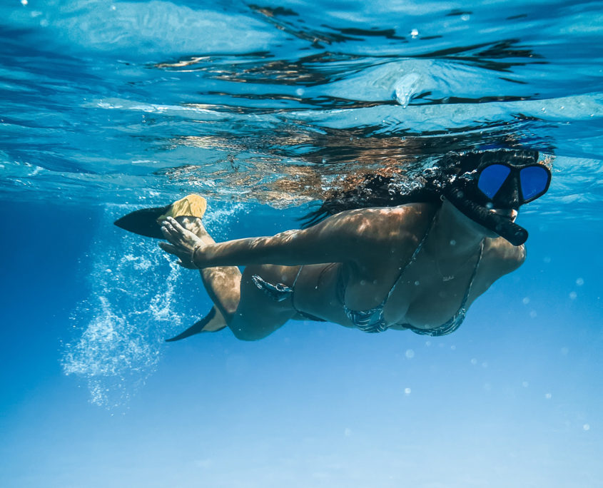 woman wearing mask and snorkel is swimming on the sea surface.