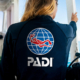 woman standin on a boat holding herself and wearing a PADI dark blue jumper