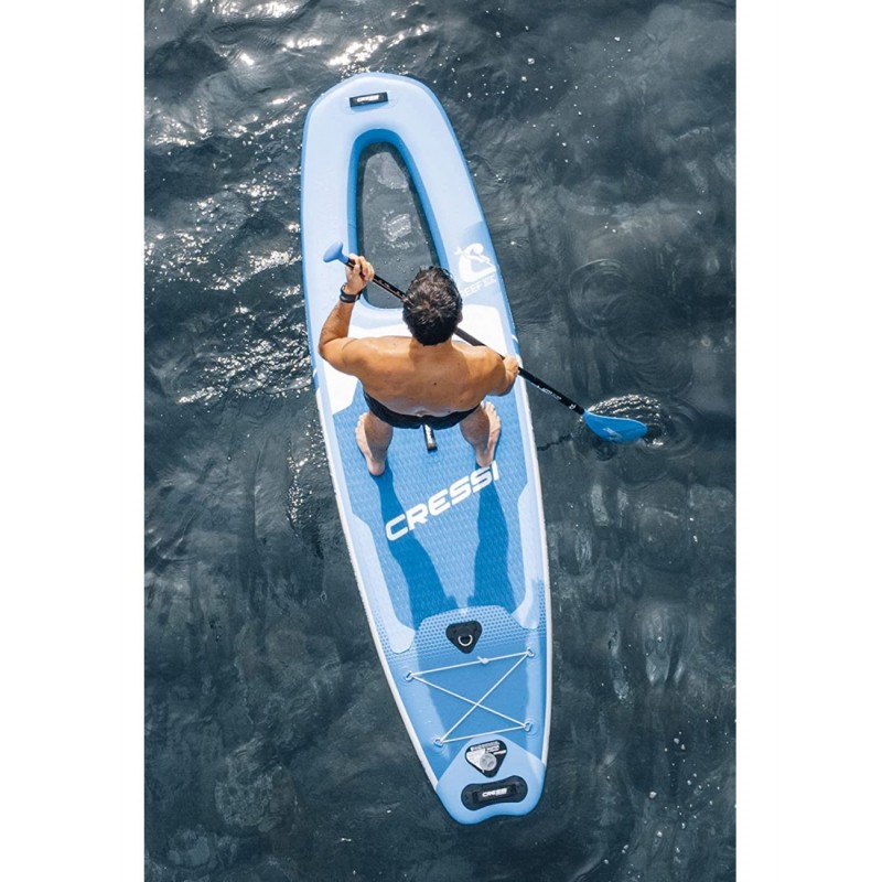 A man is standing on an inflatable paddle board in the sea